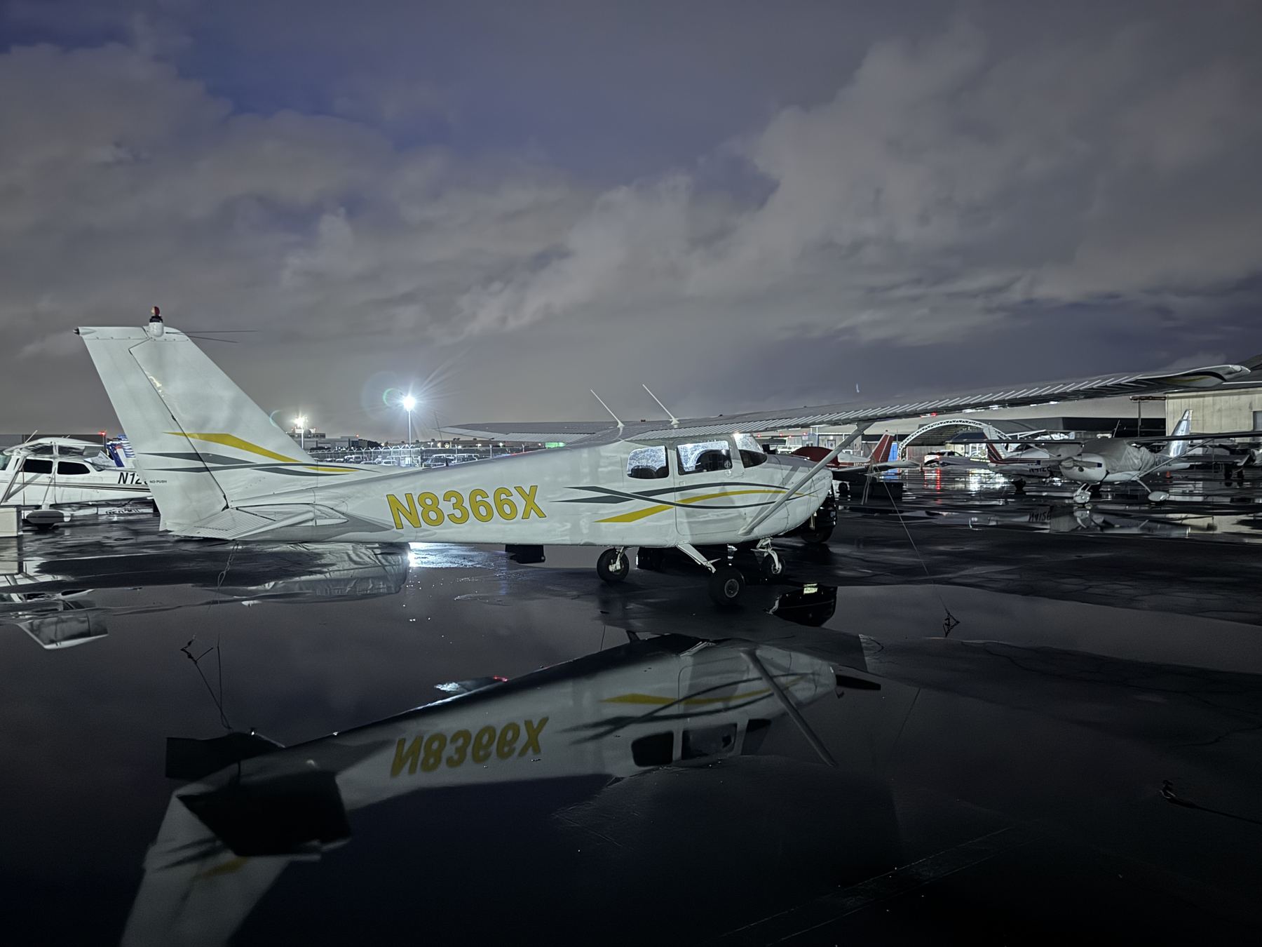 N8366X on a wet ramp at dusk, tail number visible in the reflection